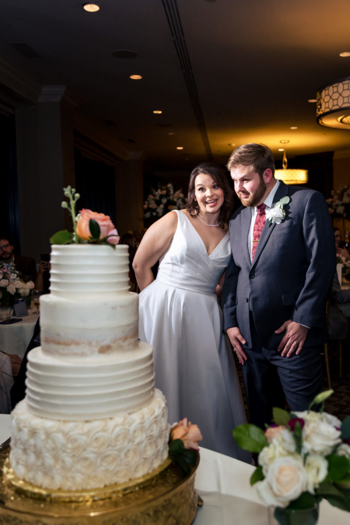 Newlyweds looking at wedding cake.