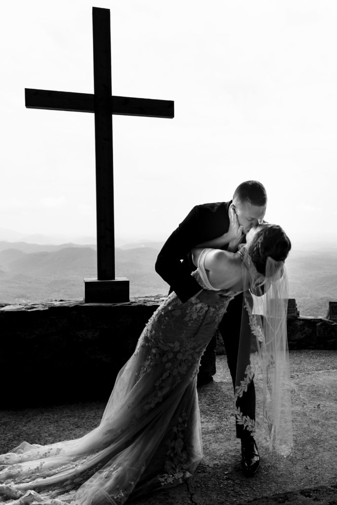 Bride and grooms first kiss with the cross at Pretty Place