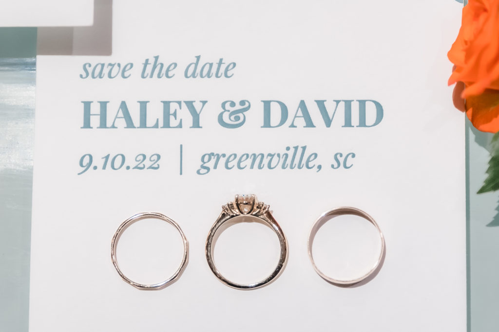 Wedding rings laying on top of wedding save the date for wedding at Zen in Greenville, SC.