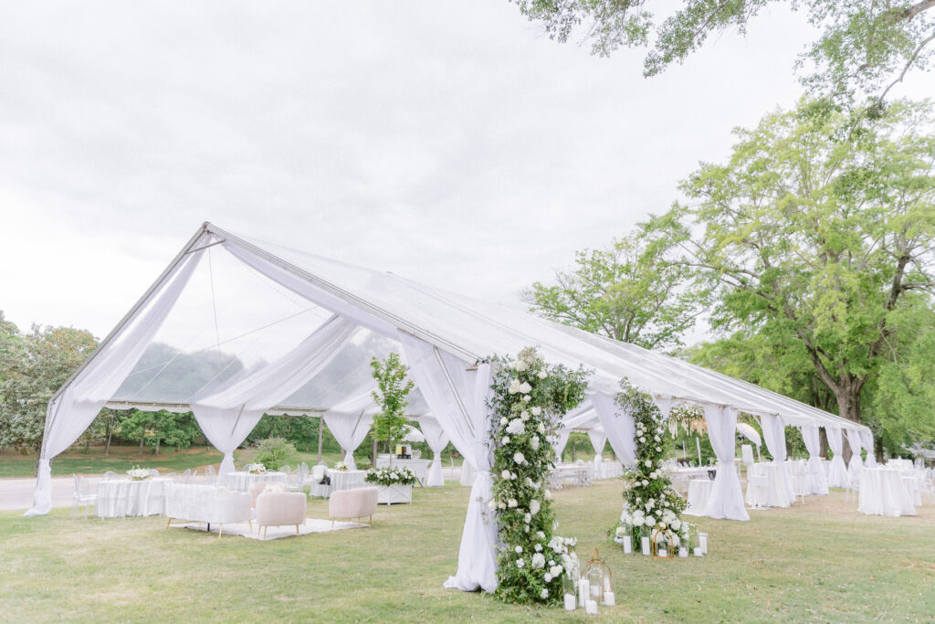 Tented wedding at a South Carolina country club with beautiful white florals and greenery climbing the entrance.