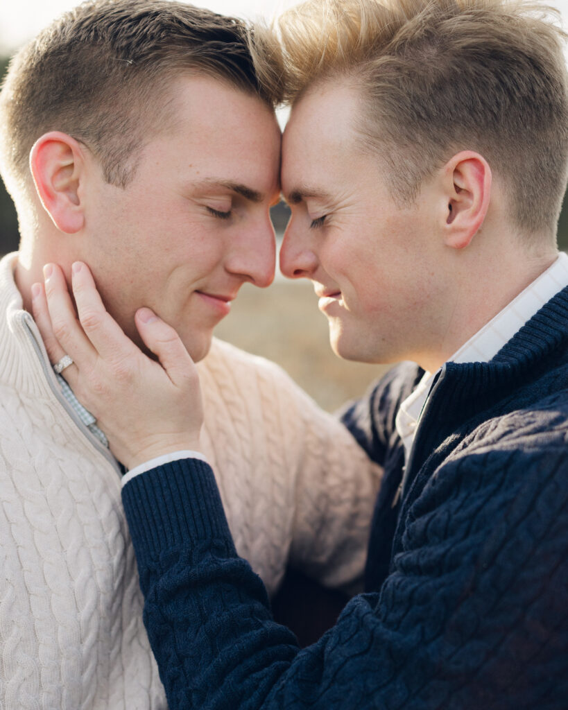 Engaged couple in coordinated cable-knit sweaters sharing an intimate moment during their engagement session