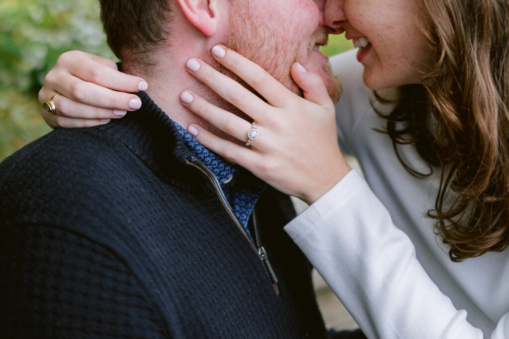 Close-up engagement photo showing a couple in coordinated textured outfits and an engagement ring